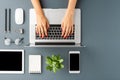 Overhead shot of womanÃ¢â¬â¢s hands working on laptop on gray table with accessories. Office desktop. Royalty Free Stock Photo